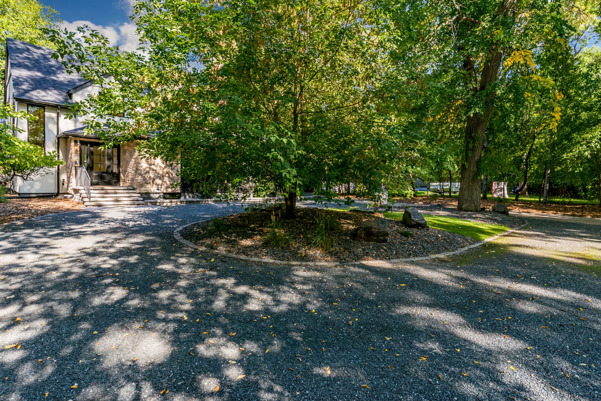 Circular gravel driveway beneath mature trees at the front entrance