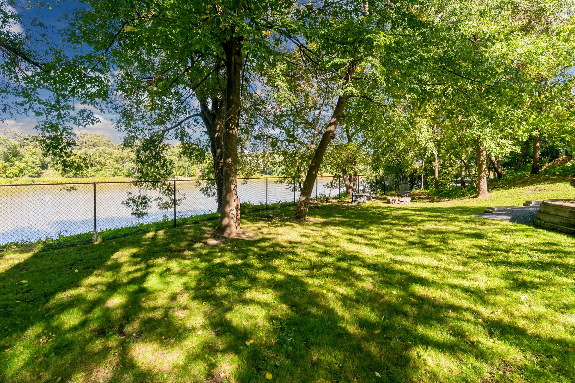 Shaded lawn running to the Red River with a fire pit and seating