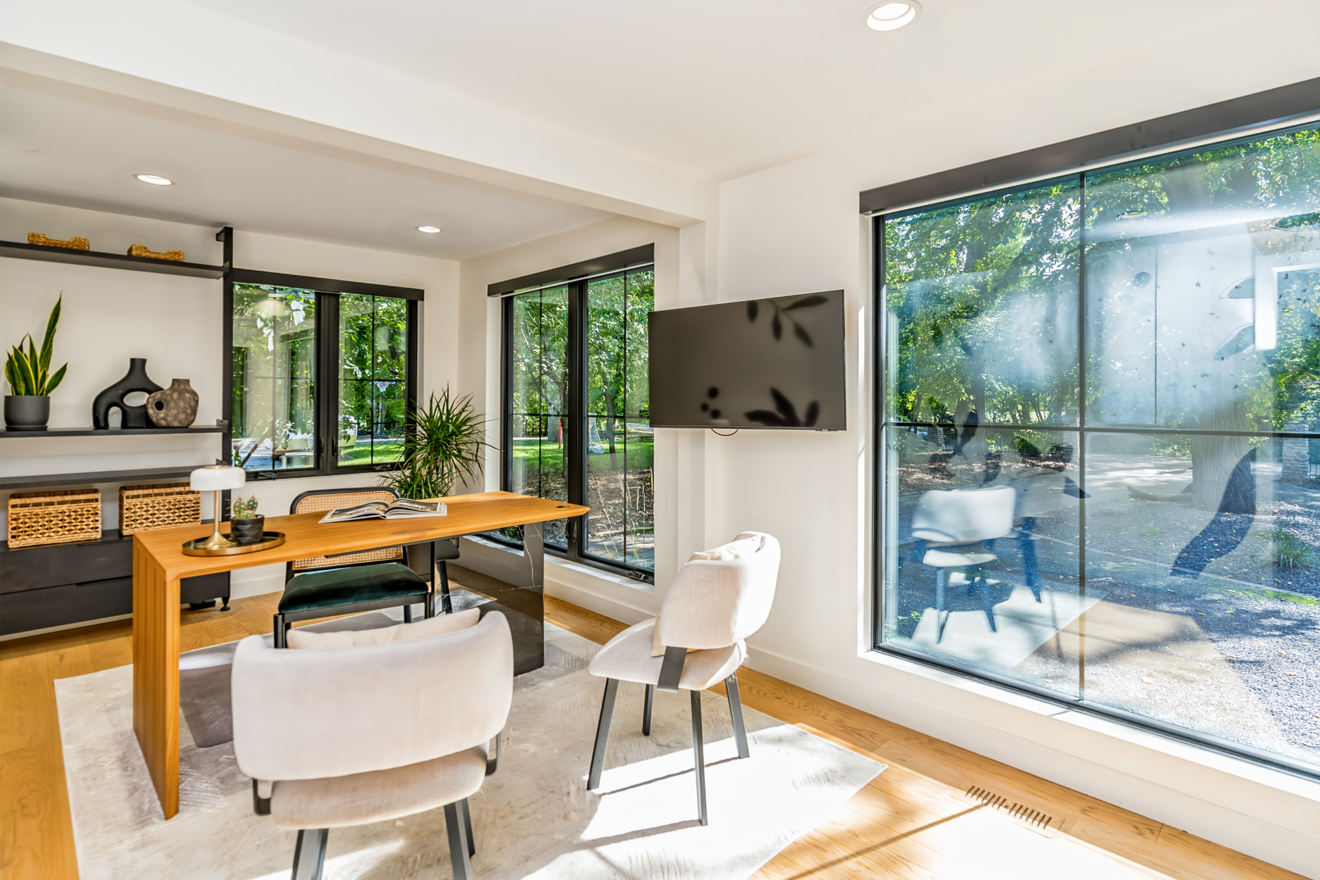 Main-floor office with wood desk and large windows overlooking the front garden