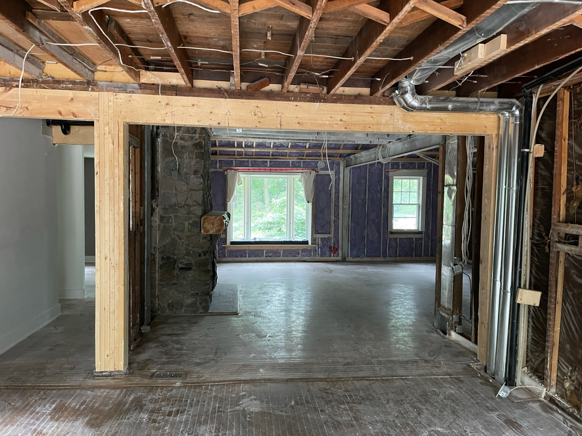 Main floor opened back to the studs, showing the new support beam and original stone fireplace
